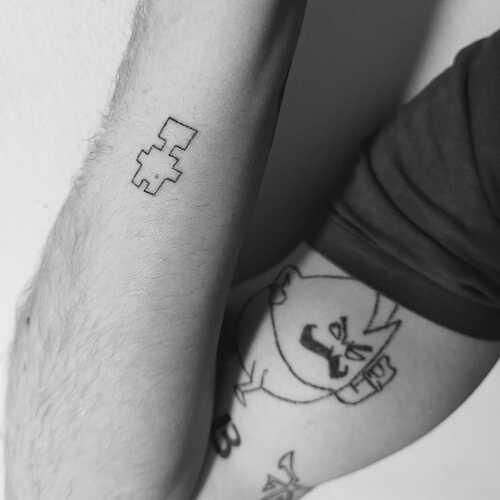 some very sketchy stick and poke tattoos in black and white. Visible in the foreground on the forearm is the titular character from Battery Acid Boy, whilst in the background on the upper arm is mustachio, the letter B and the Las Plagas symbol from RE4