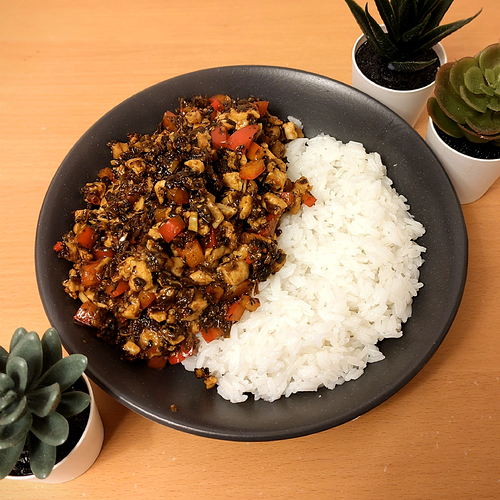 Photograph of stir fried chicken with Yibin Yacai, served with a slightly excessive portion of jasmine rice as I was starving when I got in from work. I have no remorse. At the edges of the photograph tiny fake plants are arranged in a vague attempt to make it look like I understand how to frame an image.