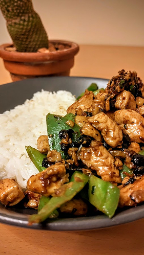 Photograph of a stir-fried chicken and green pepper dish with jasmine rice. A cactus is visible in the background.