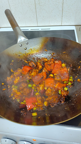 a chicken stir fry, sizzling and steaming within the work. It's full of vibrant red hues.