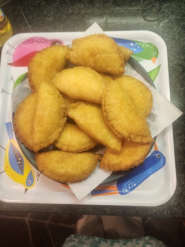 About a dozen half-moon pastries sitting on a plate.