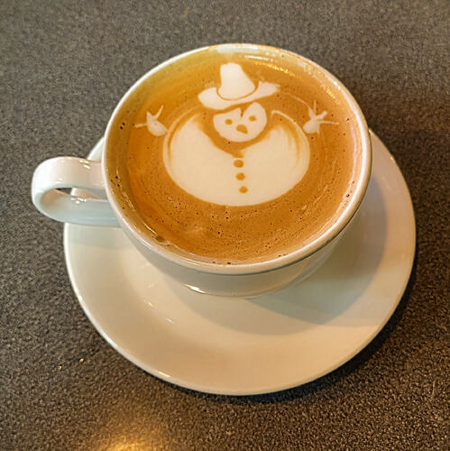 A latte with a slightly wobbly snowman as latte art