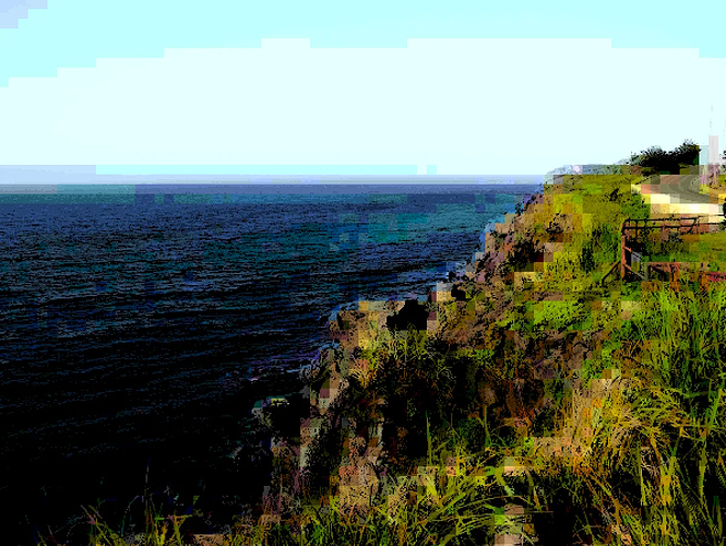 heavily processed picture of a grassy cliffside looking out onto the ocean. It features large, blocky pixels of colour, but with light and shadow rendered with much higher levels of detail. It is highly saturated