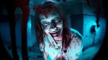Screenshot from Evil Dead Rise. A figure stares through a peephole in an apartment complex door. She has wide eyes with an unnatural hue, unkempt hair and many cuts across her face. The peephole is covered in blood.